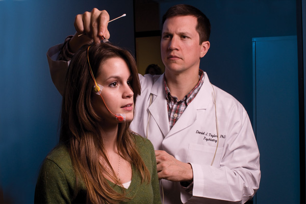 Student participates in insomnia study, with electrodes attached to her chin, side of her head and top of her head.