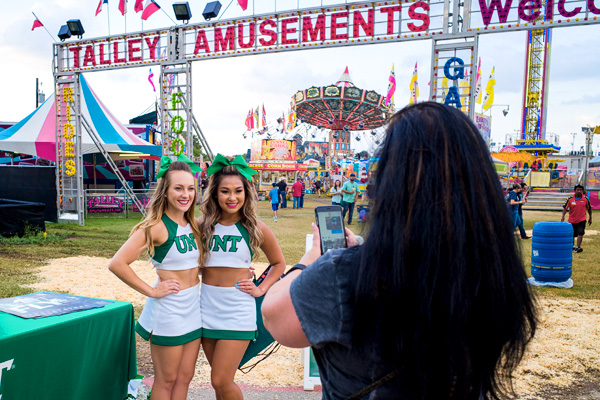 UNT cheerleaders at a fair, posing for a photo.